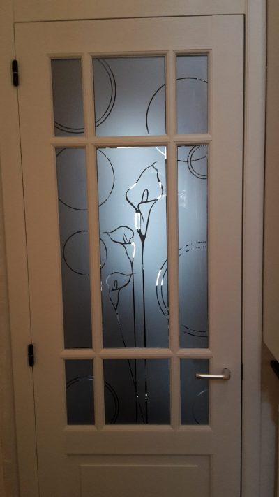 Porte intérieure à petits bois dont le vitrage porte un film à effet sablé ajouré de fleurs d'arum et de cercles