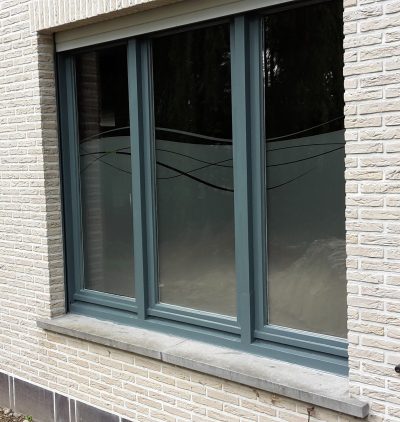 Fenêtre à trois vantaux d'une façade en briques claires avec un film à effet sablé à motif de lignes ondulées