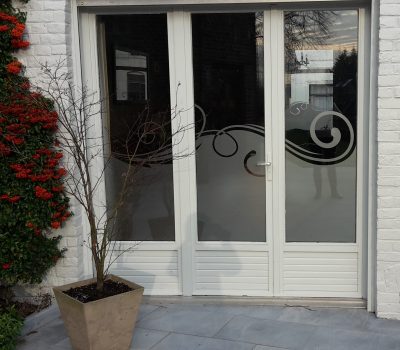 Porte-fenêtre à trois vantaux d'une maison aux briques peintes en blanc, film à effet sablé à motif de grandes volutes