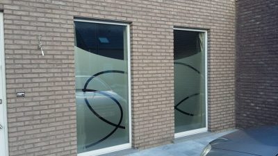 Deux fenêtres hautes d'une façade en briques avec un film à effet sablé à motif de grands cercles entrecroisés