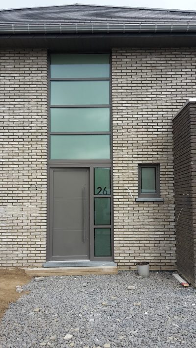 Porte d'entrée d'une maison en briques claires, imposte et panneau latéral en film à effet sablé, numéro 26 en adhésif