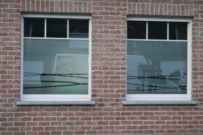 Deux fenêtres d'une façade en briques avec un film à effet sablé à motif de lignes ondulées entrecroisées