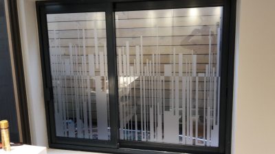 Baie coulissante vue de l'intérieur, film à effet sablé à motif de bandes verticales de hauteurs variées