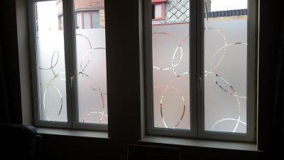 Fenêtres vues de l'intérieur, film à effet sablé ajouré de grands cercles entrelacés qui laissent voir dehors
