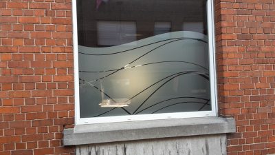 Fenêtre d'une façade en briques rouges avec un film à effet sablé à motif de vagues ondulées