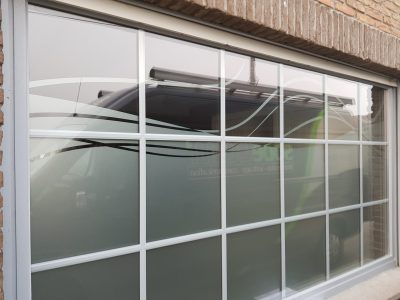Grande fenêtre à croisillons d'une façade en briques dont le vitrage porte un film à effet sablé ajouré de vagues entrelacées