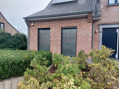 Deux fenêtres hautes d'une façade en briques rouges dont le vitrage porte un film à effet sablé plein traversé de fines lignes horizontales et verticales