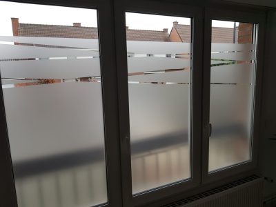 Fenêtre blanche à trois vantaux dont le vitrage porte un film à effet sablé plein en partie basse, dégagé de bandes horizontales en partie haute