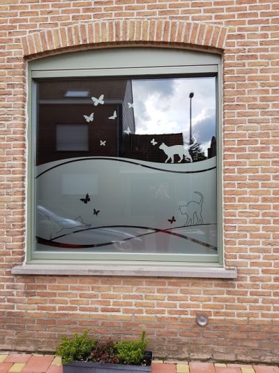 Fenêtre d'une façade en briques avec un film sur mesure à motif de chats et de papillons posés sur une vague