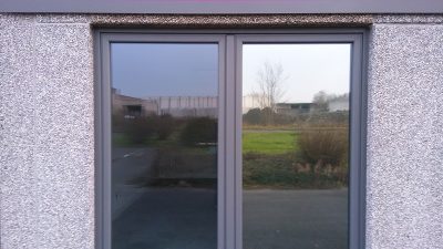 Porte-fenêtre à deux vantaux dont un seul est équipé d'un film solaire teinté, la différence de teinte est visible
