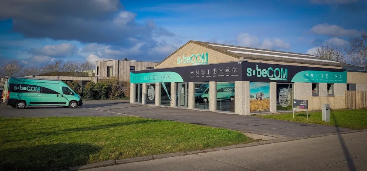 Le bâtiment Sobecom vu depuis la rue, son enseigne et ses vitrines habillées sur toute la longueur de la façade
